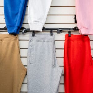A wall with several different colored sweatpants hanging.