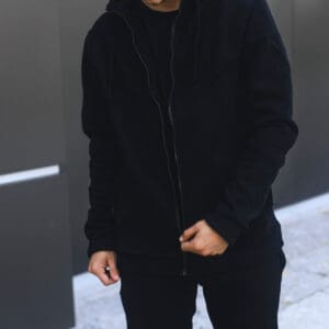 A man in black jacket standing on sidewalk.