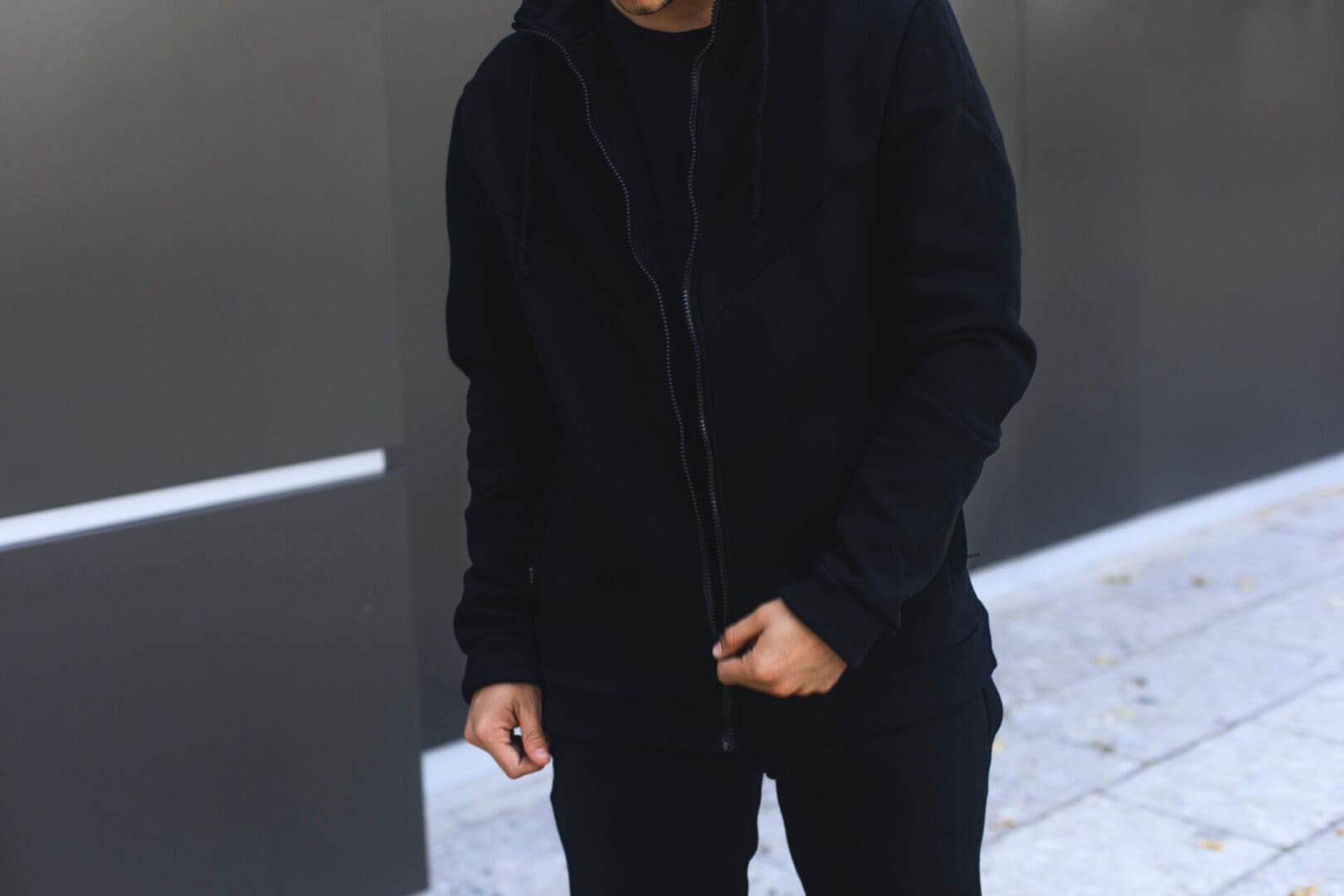 A man in black jacket standing on sidewalk.