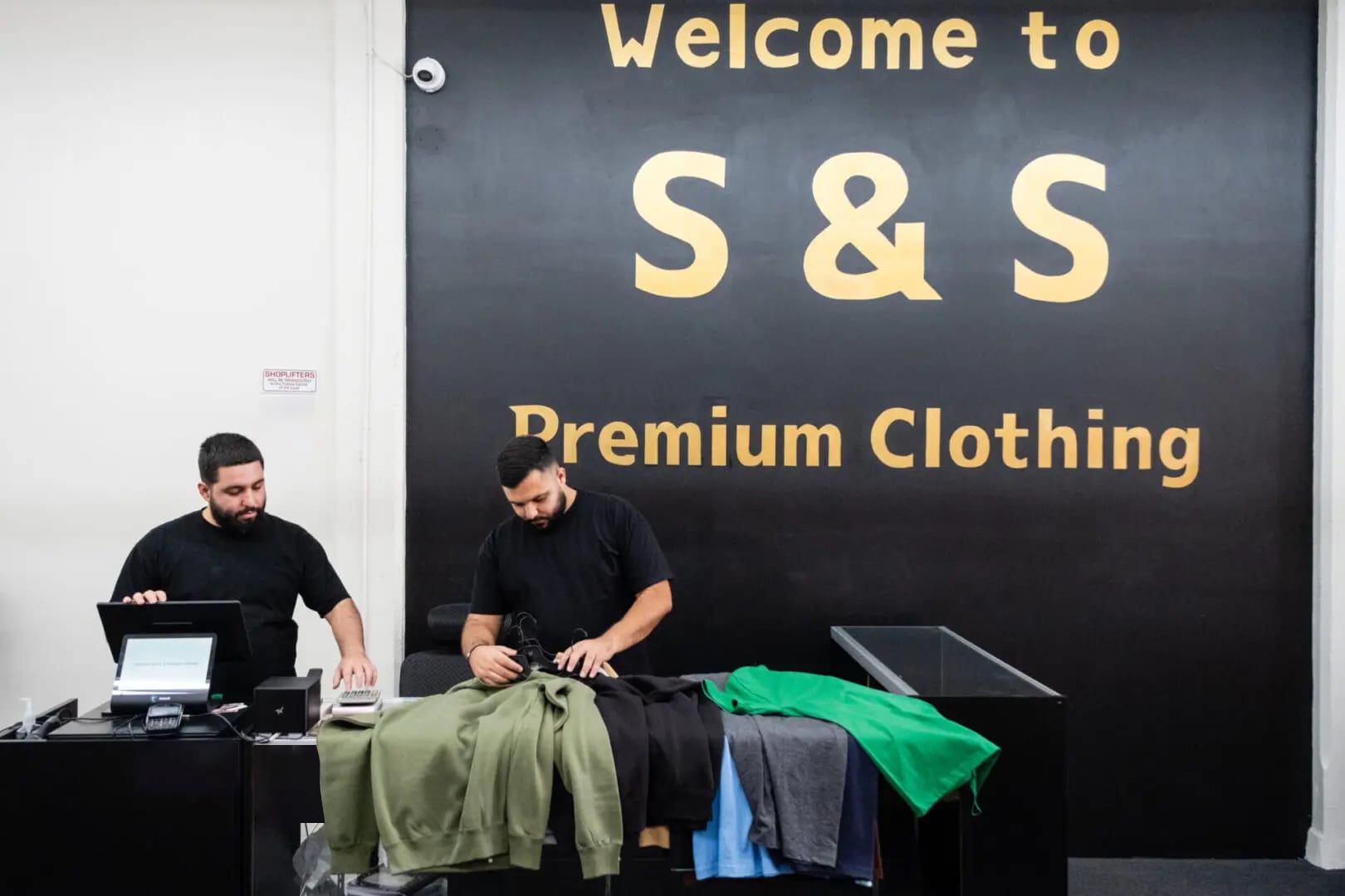 Two men are ironing clothes on a table.